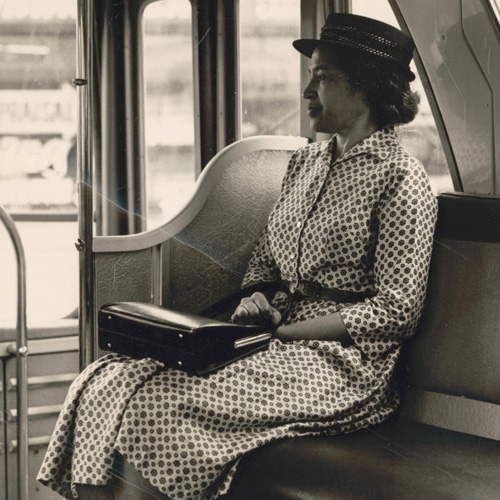 Rosa Parks seated in the front of a public bus, likely a staged photograph